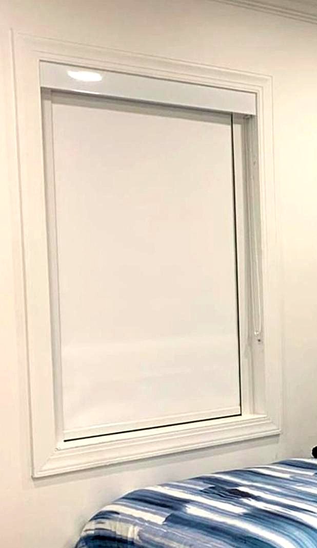 White blackout roller shade with cassette and side channels in a bedroom